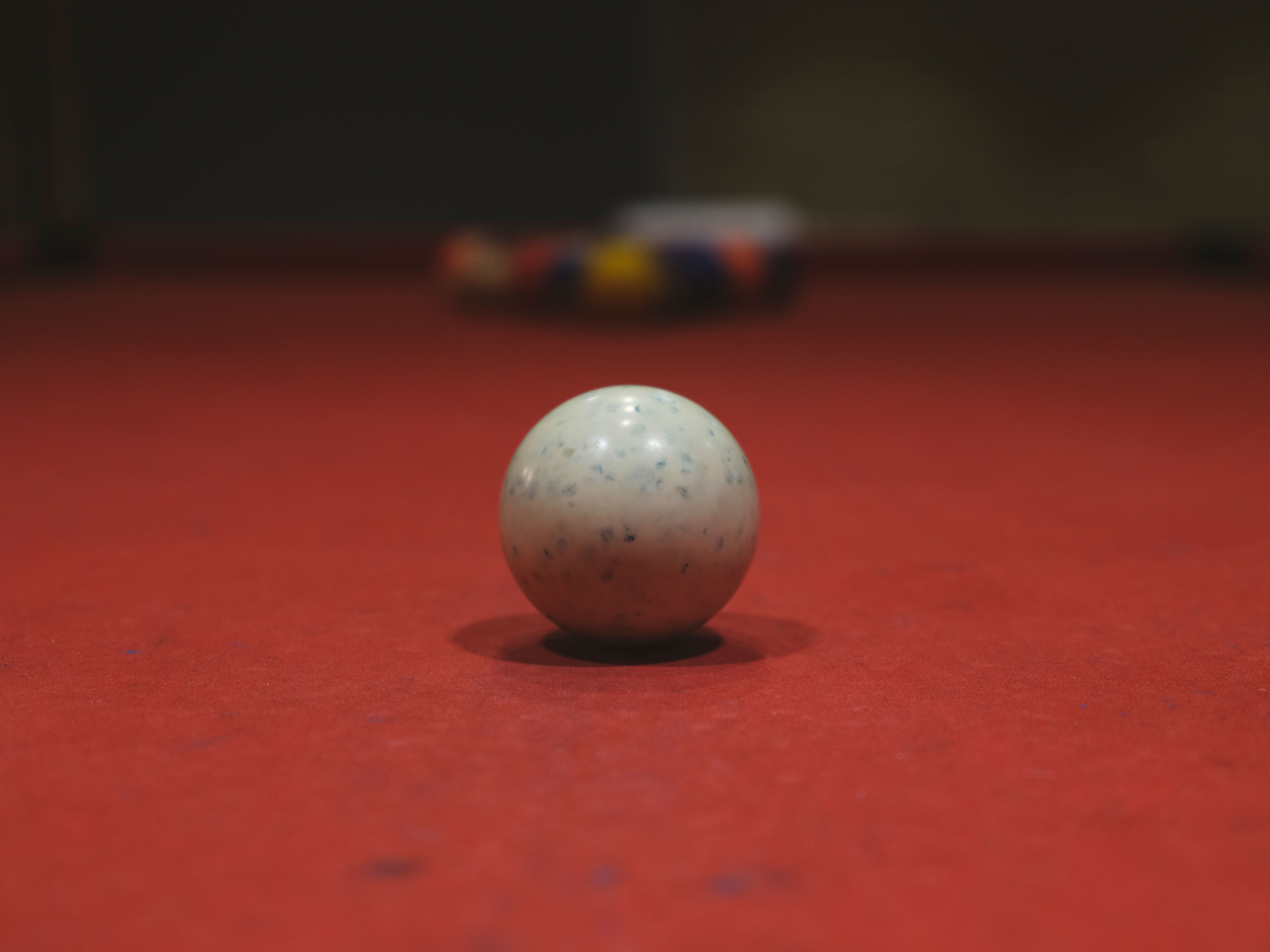 A detailed shot of a billiard ball on a red pool table surface with blurred background.
